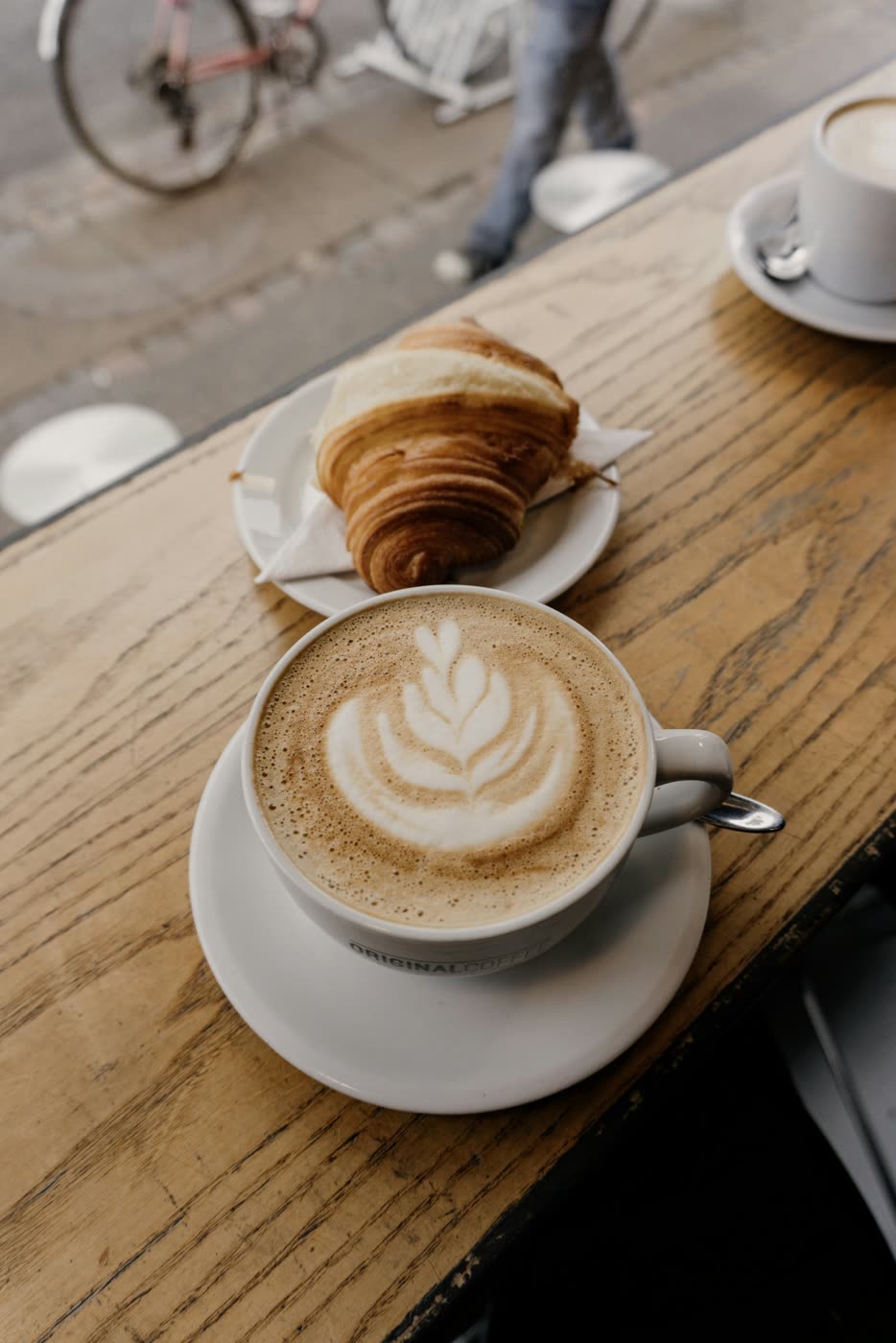 Cappuccino mit Latte-Art und frisches Croissant