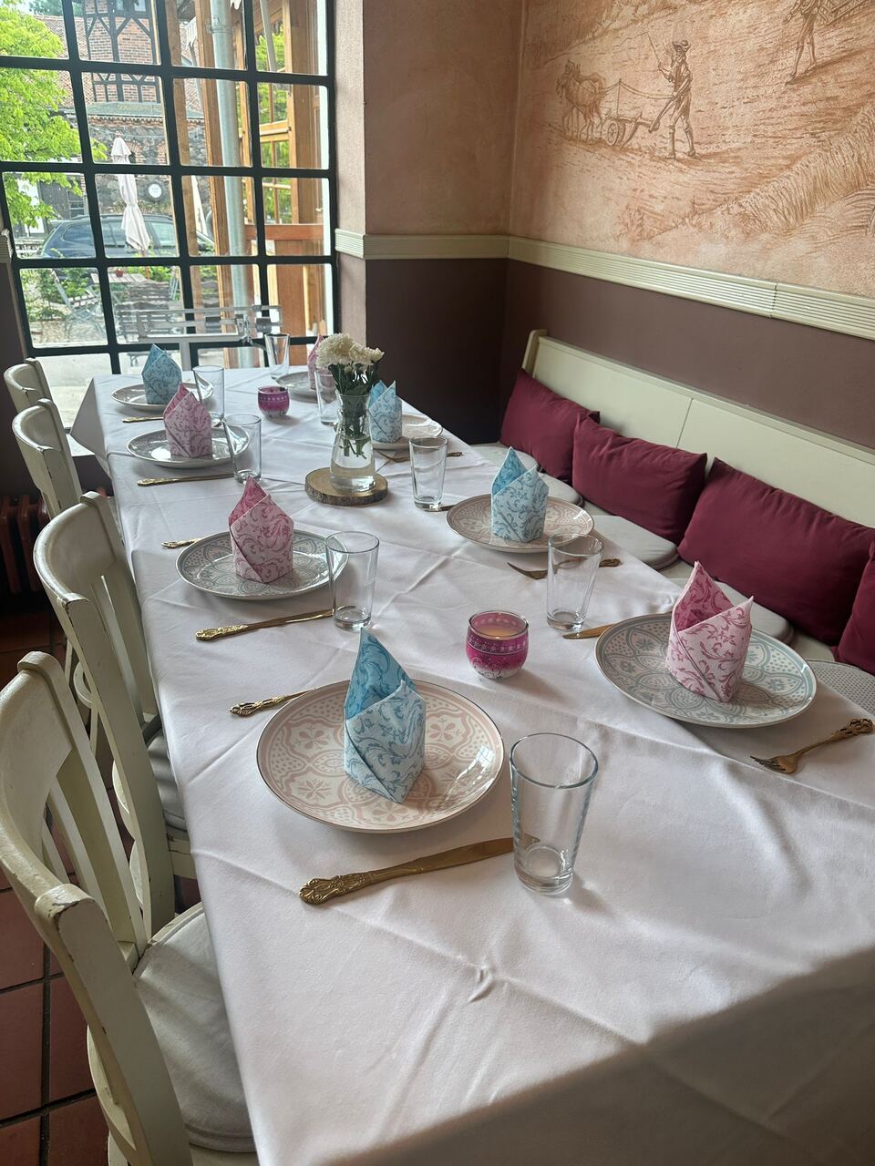 Lange festlich gedeckte Tafel mit blauen und rosa Servietten im Café-Saal